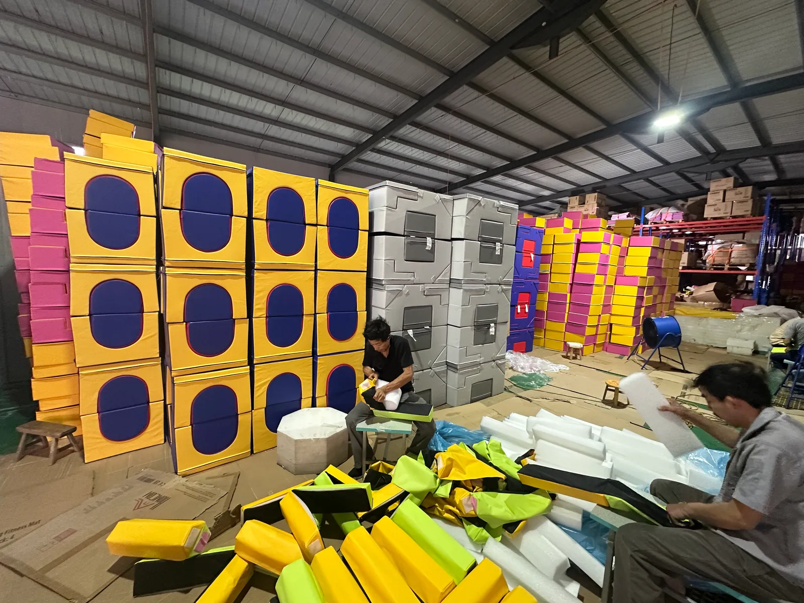 Workers fitting foam cores into sewn covers for soft play blocks and plyo boxes